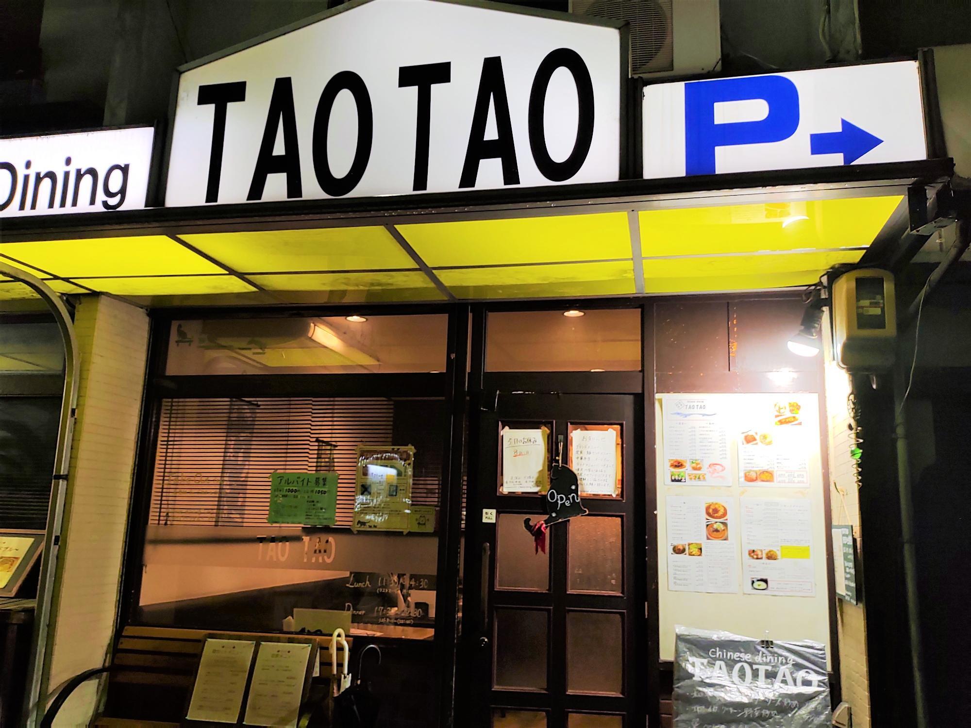 TAO TAO の外観。入口のメニューや掲示物が写っている夜の様子。