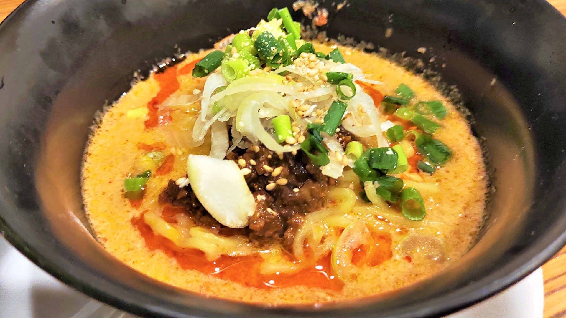 白胡麻担々麺のアップ写真。濃厚なスープに肉味噌、白ねぎ、青ねぎがのった一杯。