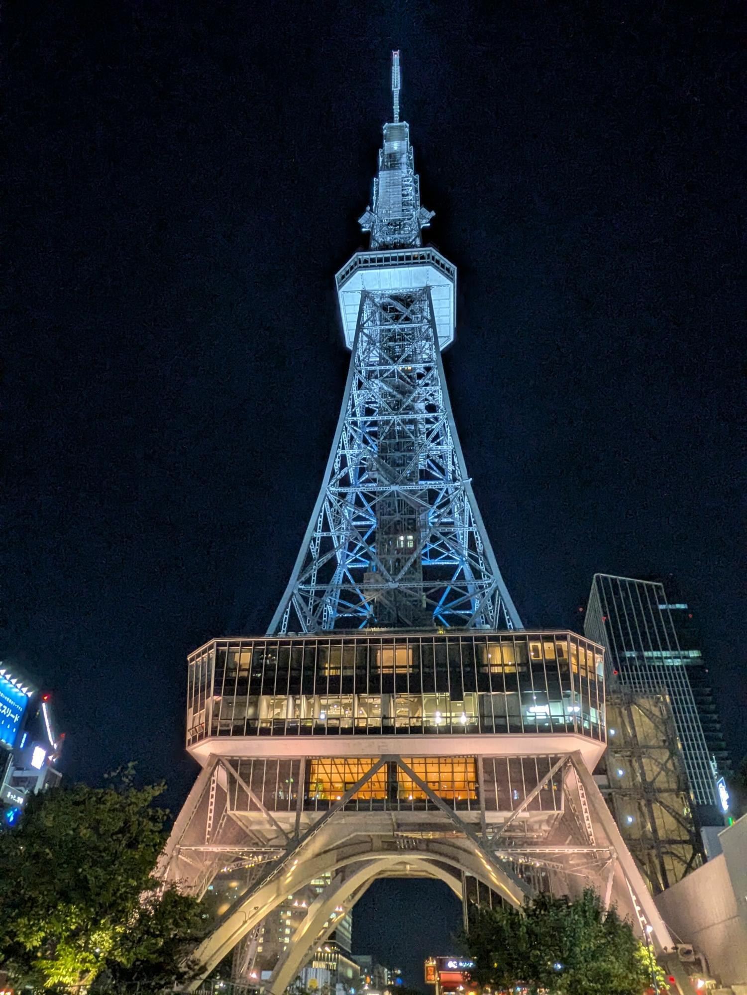 夜の空にライトアップされたタワーが立ち、周囲の街並みが広がっている様子。