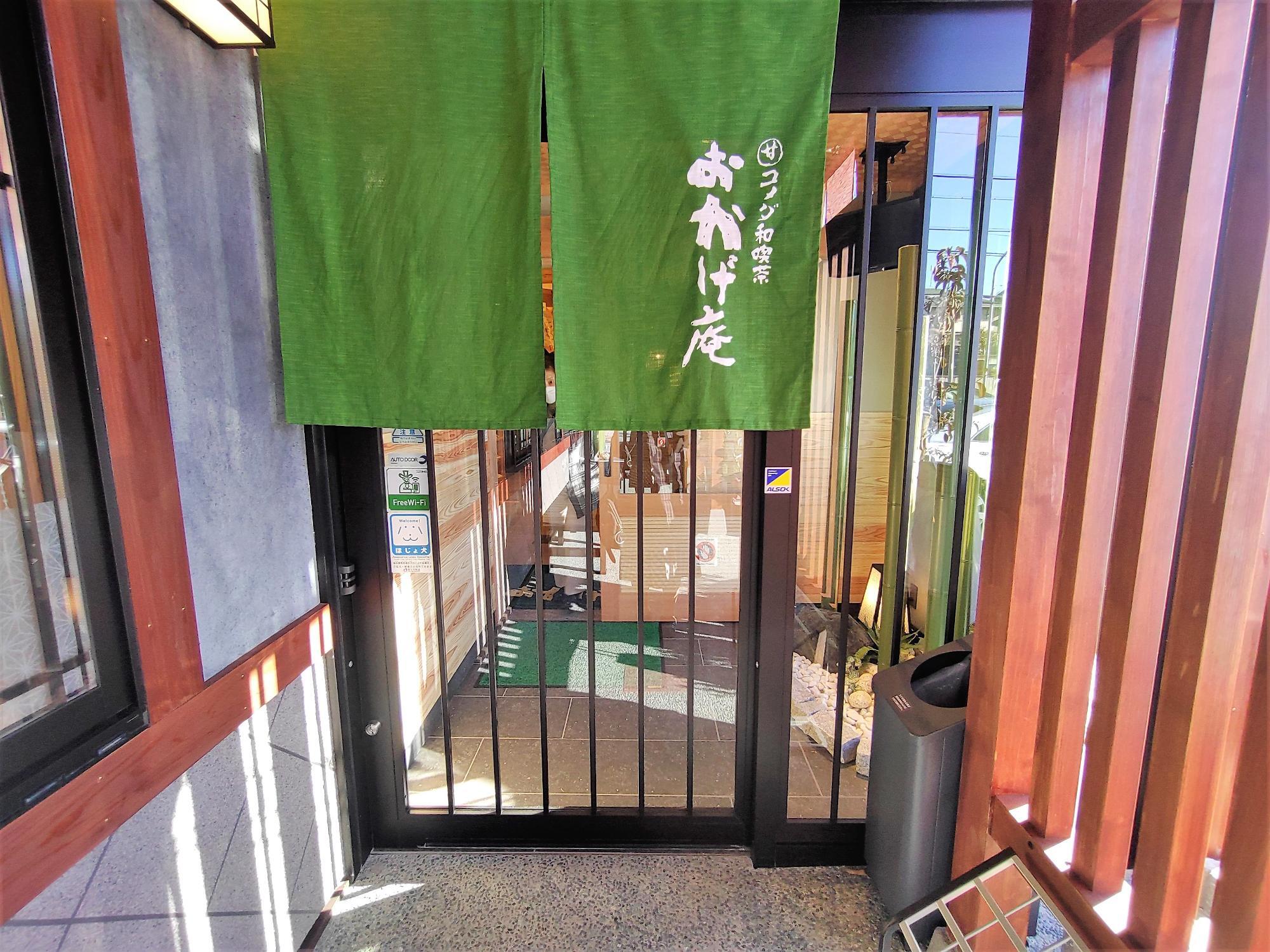 おかげ庵の入口。緑色ののれんとガラス扉が並ぶ落ち着いた外観。