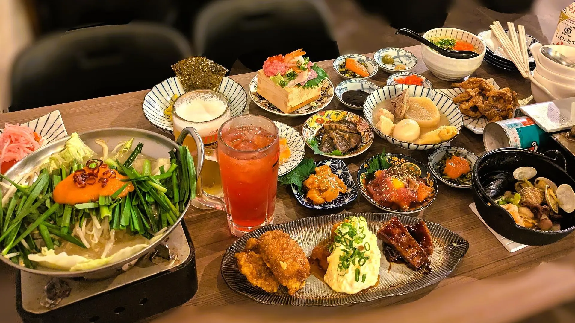 おすすめ屋の食べ飲み放題メニュー。もつ煮込みや豚骨おでんをはじめ、多彩な小皿料理がテーブルいっぱいに並ぶ様子。