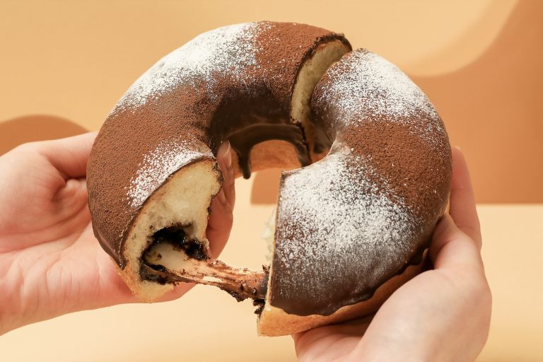 アンティークの新作もちもちチョコもっちーリングを手で割った様子。柔らかい生地からとろりと伸びるチョコと餅が見えるアップ写真。」