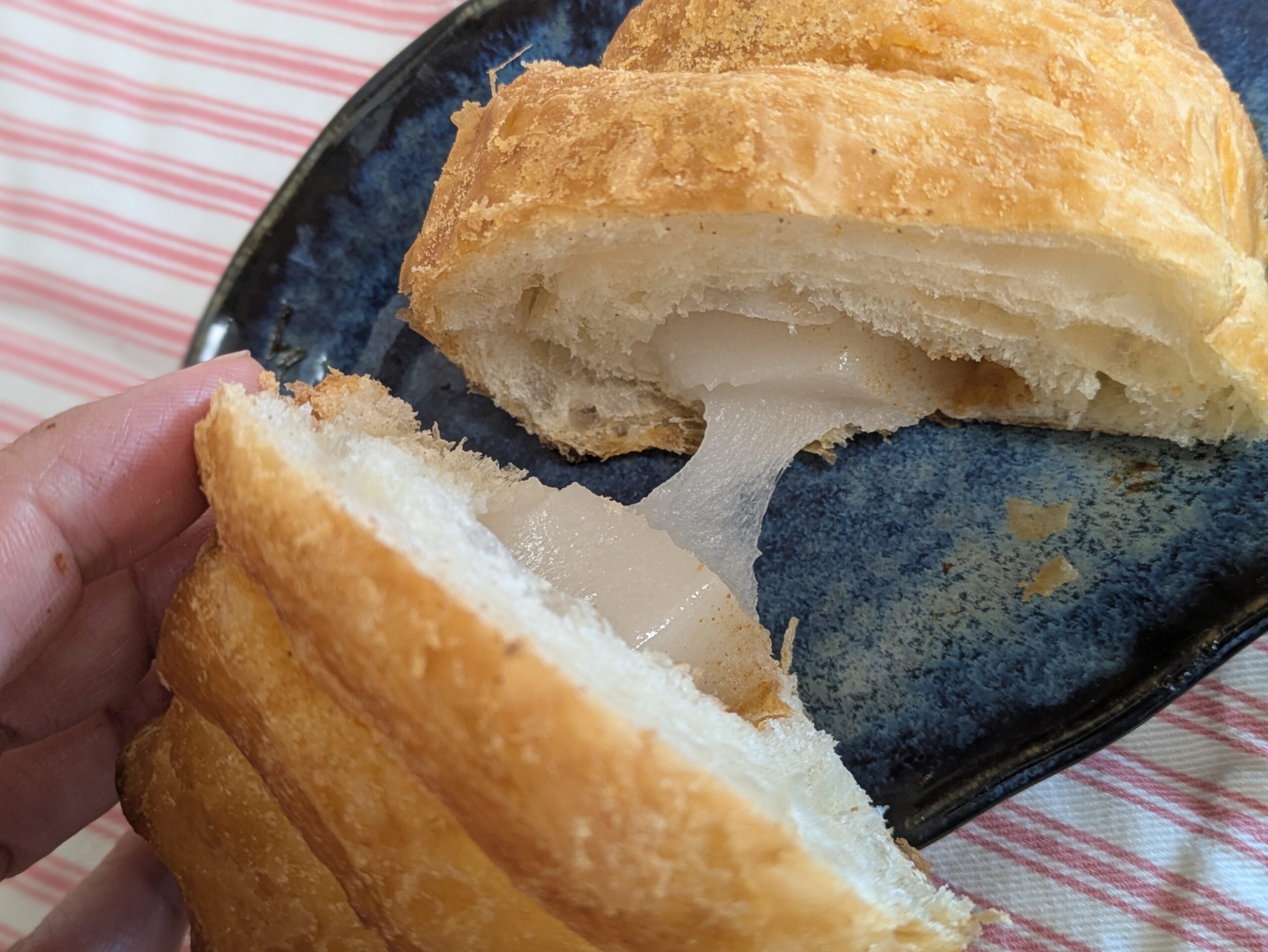 割ったクロッチの中から、お餅がとろりと伸びる様子。サクッとした層ともっちり食感が伝わるアップ写真。冷めても伸びるお餅が印象的。