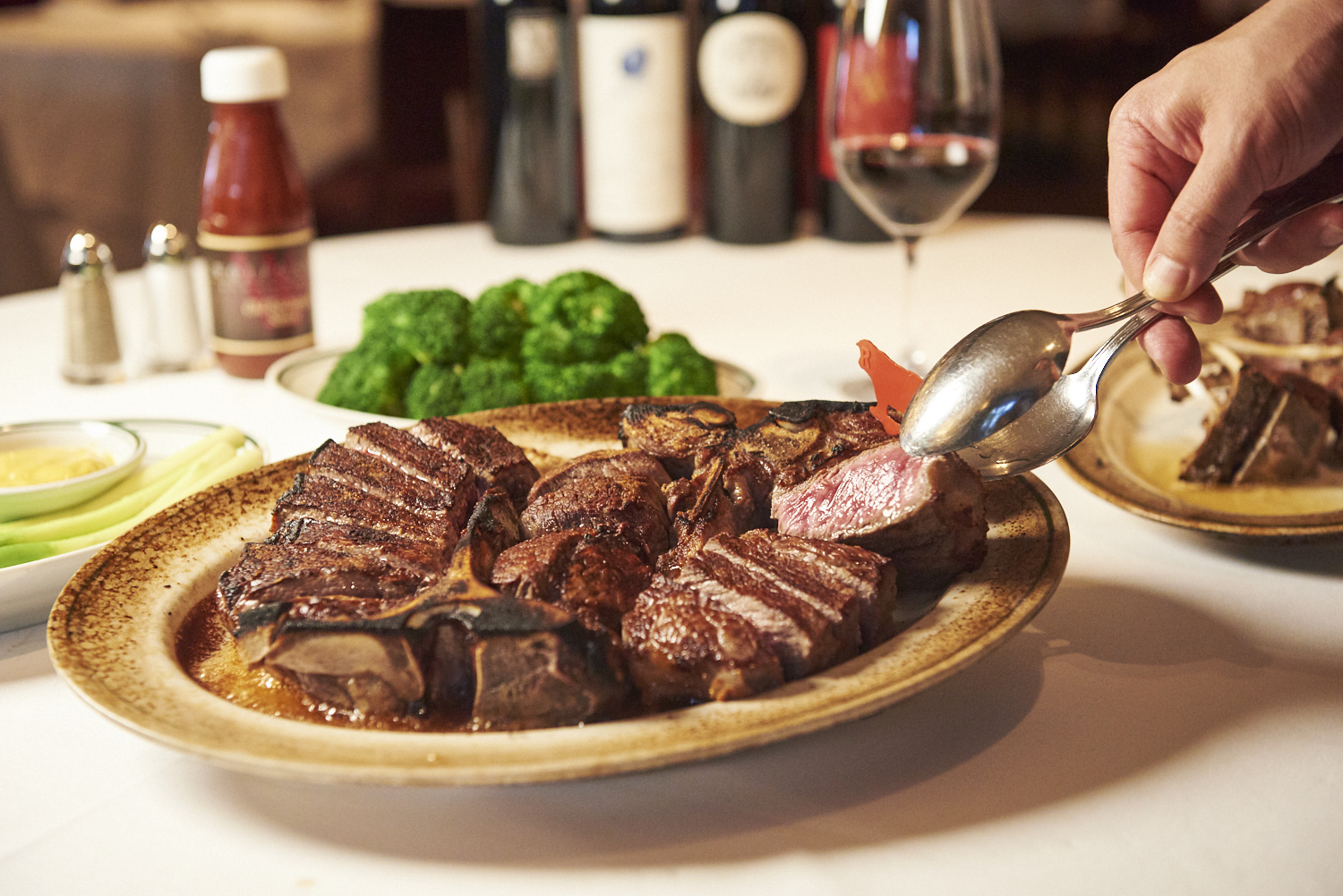 ウルフギャング・ステーキハウスのUSDAプライム熟成肉ステーキ。焼き目が美しい厚切り肉を取り分ける様子