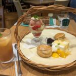 スコーンやパフェ、ケーキが並ぶアフタヌーンティーセットとアイスティーの、落ち着いたカフェテーブル